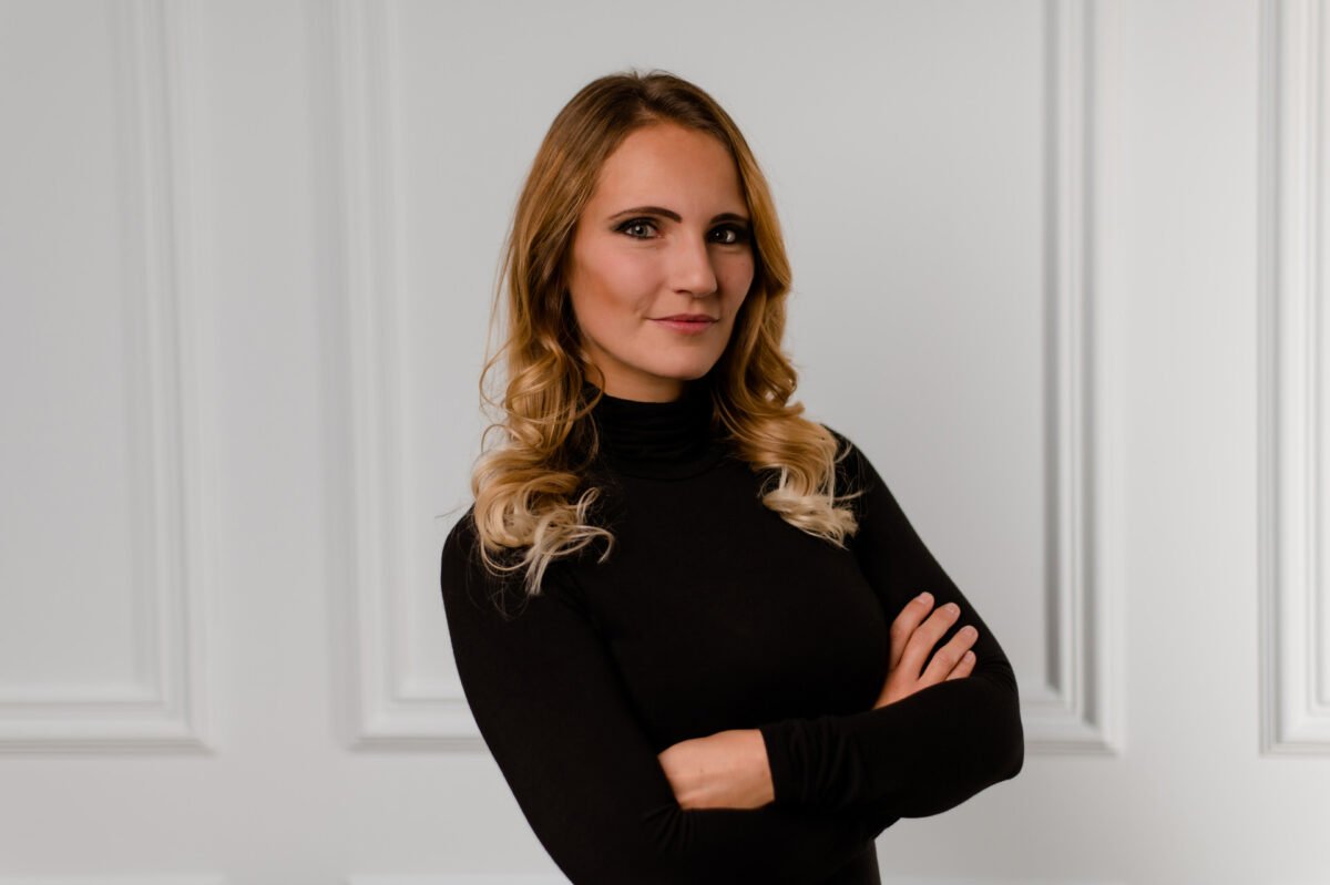 Christian Lorenz Fotograf Eine Frau mit langem, gewelltem, blond-braunem Haar steht mit verschränkten Armen und einem schwarzen Rollkragenpullover vor einer weiß getäfelten Wand. Sie hat einen selbstbewussten Gesichtsausdruck. Christian Lorenz Fotograf Eine Frau mit langem, gewelltem, blond-braunem Haar steht mit verschränkten Armen und einem schwarzen Rollkragenpullover vor einer weiß getäfelten Wand. Sie hat einen selbstbewussten Gesichtsausdruck.