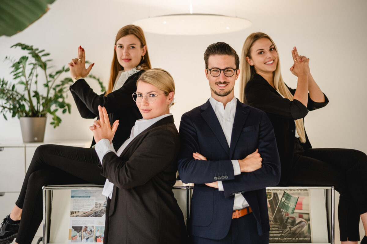 Christian Lorenz Fotograf Vier Geschäftsleute posieren selbstbewusst in einem Büro; zwei Frauen sitzen auf den Schreibtischen dahinter und machen spielerische Gesten mit den Fingern, während ein Mann und eine weitere Frau davor stehen, lächeln und die Arme verschränken. Christian Lorenz Fotograf Vier Geschäftsleute posieren selbstbewusst in einem Büro; zwei Frauen sitzen auf den Schreibtischen dahinter und machen spielerische Gesten mit den Fingern, während ein Mann und eine weitere Frau davor stehen, lächeln und die Arme verschränken.