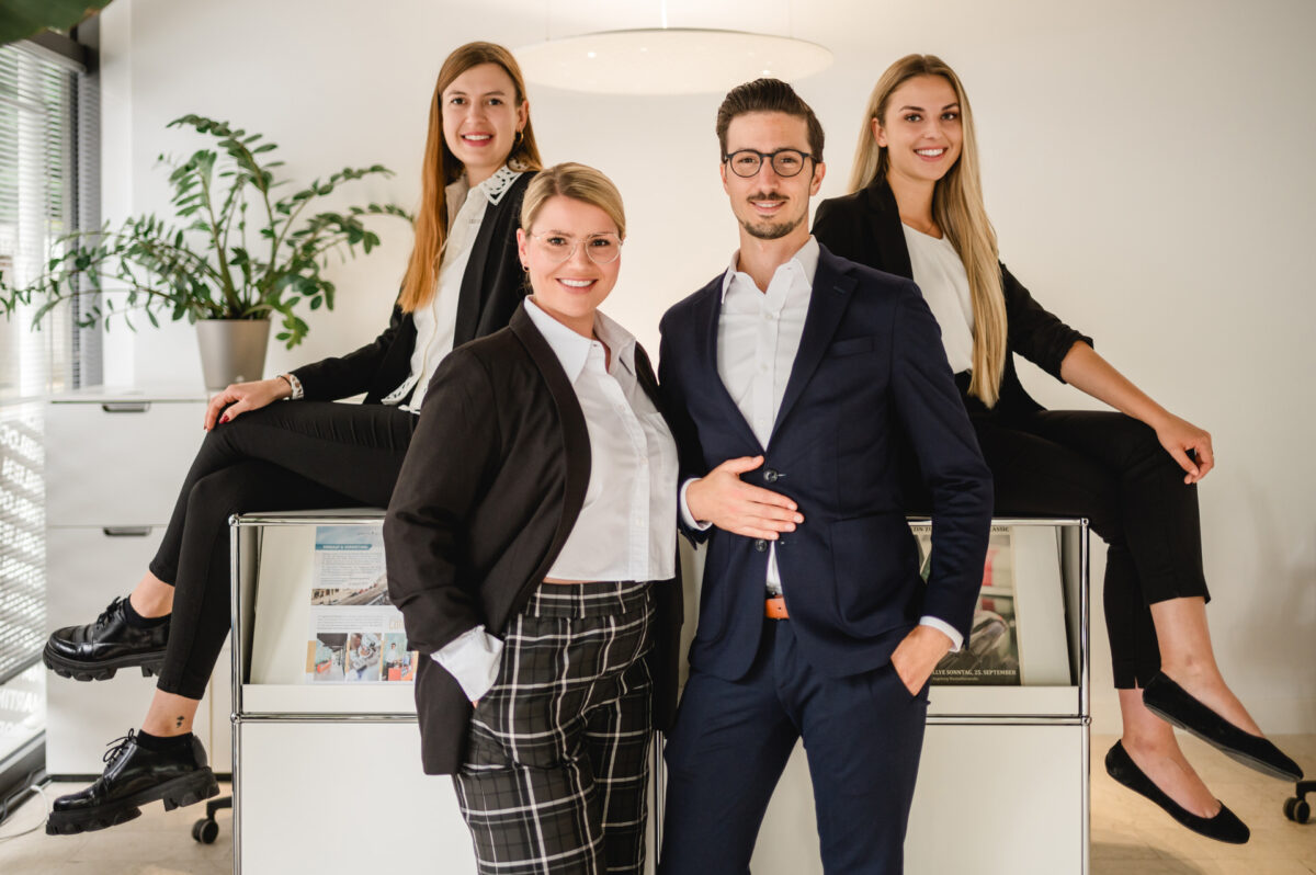 Christian Lorenz Fotograf Vier junge Berufstätige, drei Frauen und ein Mann, in Geschäftskleidung, posieren selbstbewusst und lächelnd in einem modernen Büroraum mit weißen Wänden, natürlichem Licht und einer Grünpflanze im Hintergrund. Christian Lorenz Fotograf Vier junge Berufstätige, drei Frauen und ein Mann, in Geschäftskleidung, posieren selbstbewusst und lächelnd in einem modernen Büroraum mit weißen Wänden, natürlichem Licht und einer Grünpflanze im Hintergrund.