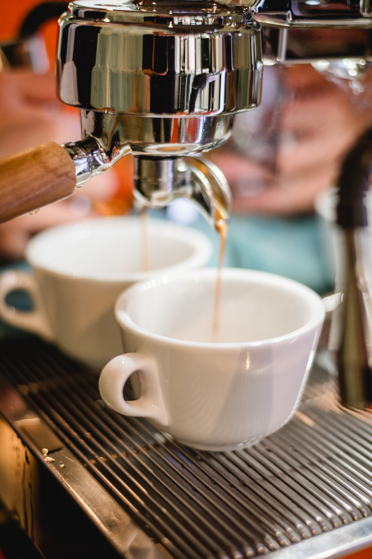 Christian Lorenz Fotograf Nahaufnahme einer Espressomaschine, die den Kaffee in zwei weiße Keramiktassen gießt, die nebeneinander auf einer Metallabtropfschale stehen. Christian Lorenz Fotograf Nahaufnahme einer Espressomaschine, die den Kaffee in zwei weiße Keramiktassen gießt, die nebeneinander auf einer Metallabtropfschale stehen.